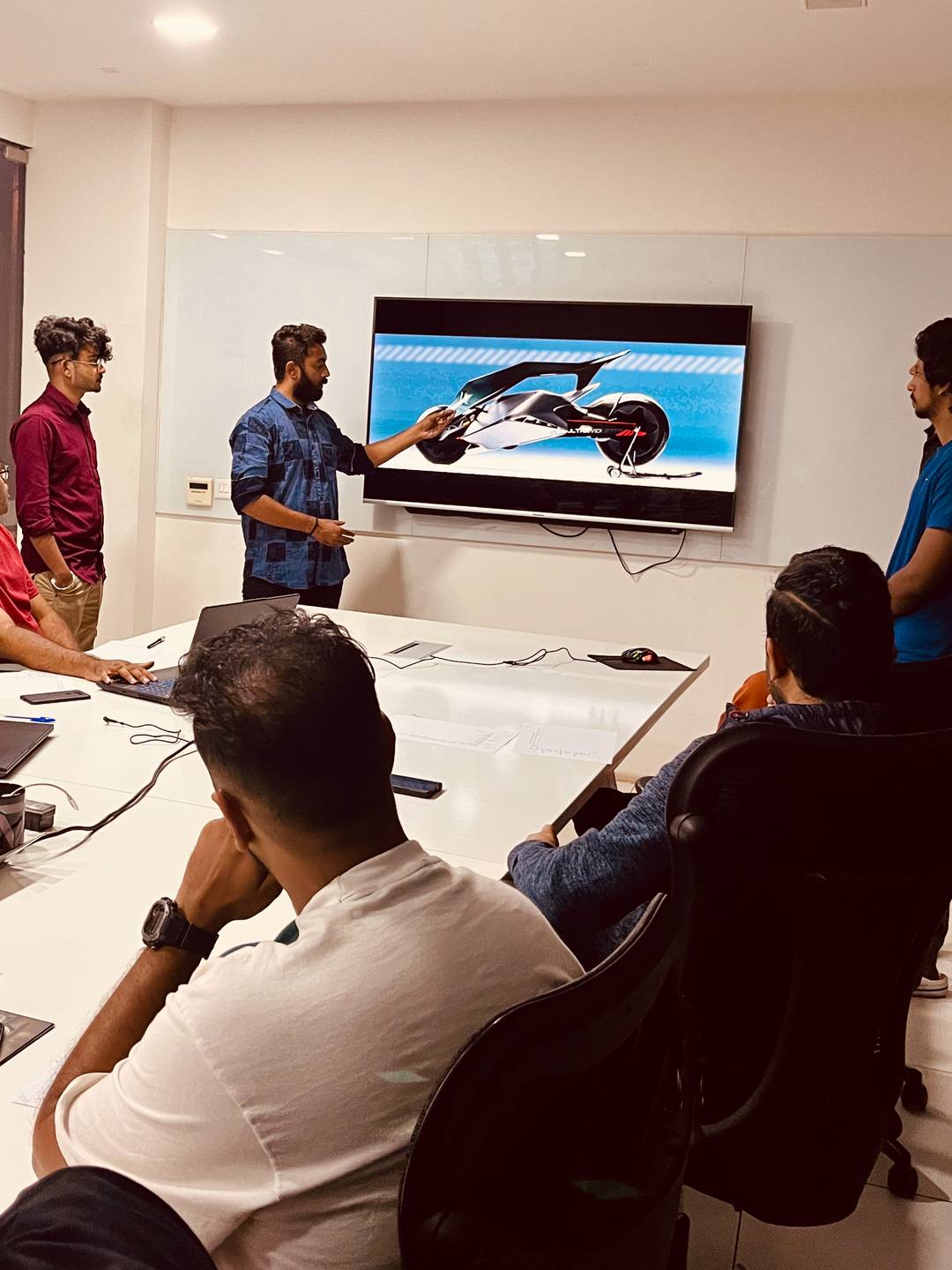 a group of design students presenting their futuristic two wheeler designs on a tv.