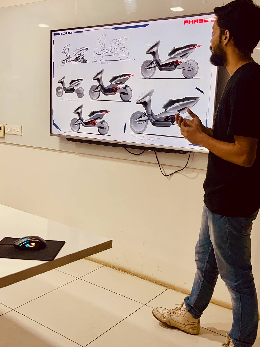 a design student presenting his two wheeler scooter design proposals on a 55inch tv.
