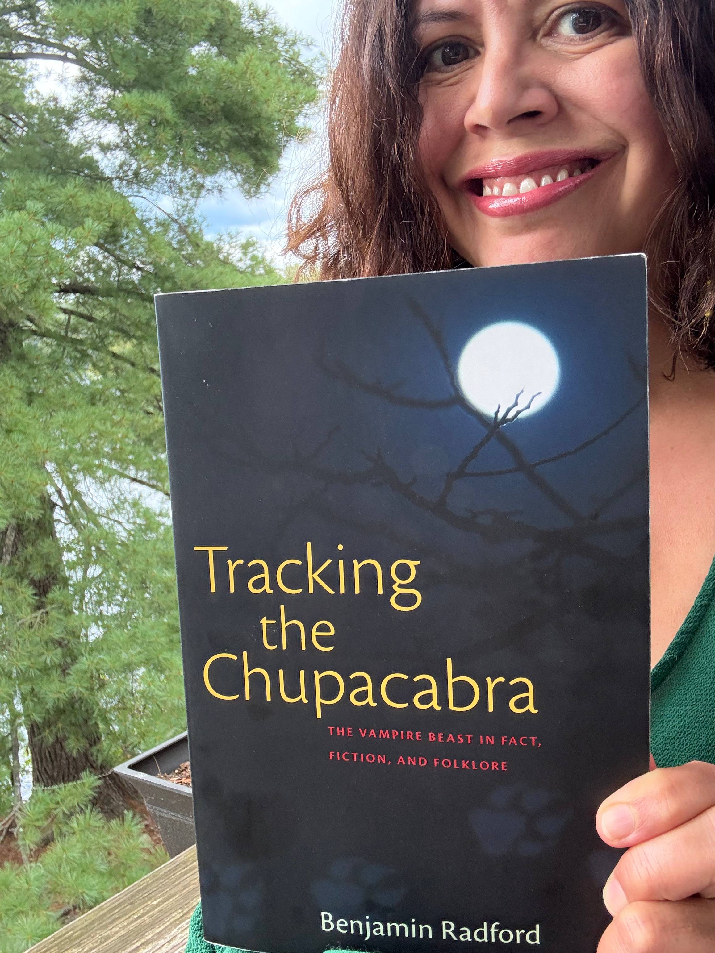 Maria Rodriguez Bross holding book called "Tracking the Chupacabra" 