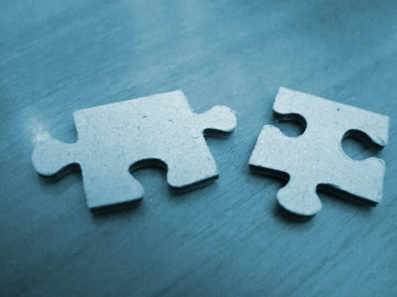 Two blue puzzle pieces separated on a wooden surface