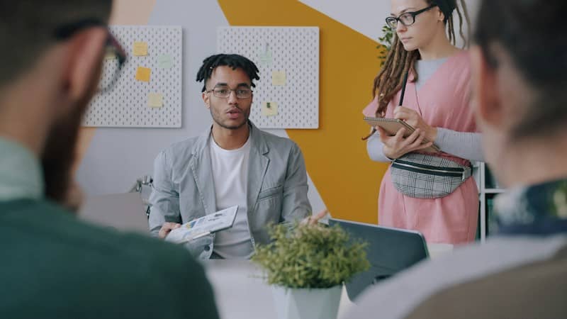 A man presenting a document to colleagues in a modern office workspace
