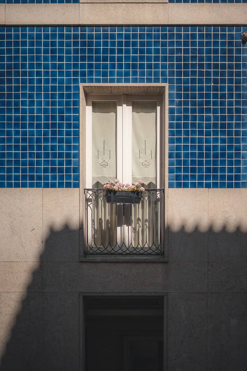 Balcony with flowers on a tiled blue building