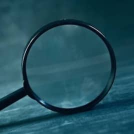 A magnifying glass rests on a textured surface.