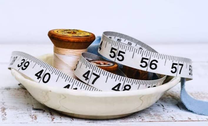 Spools and measuring tape in a decorative dish.