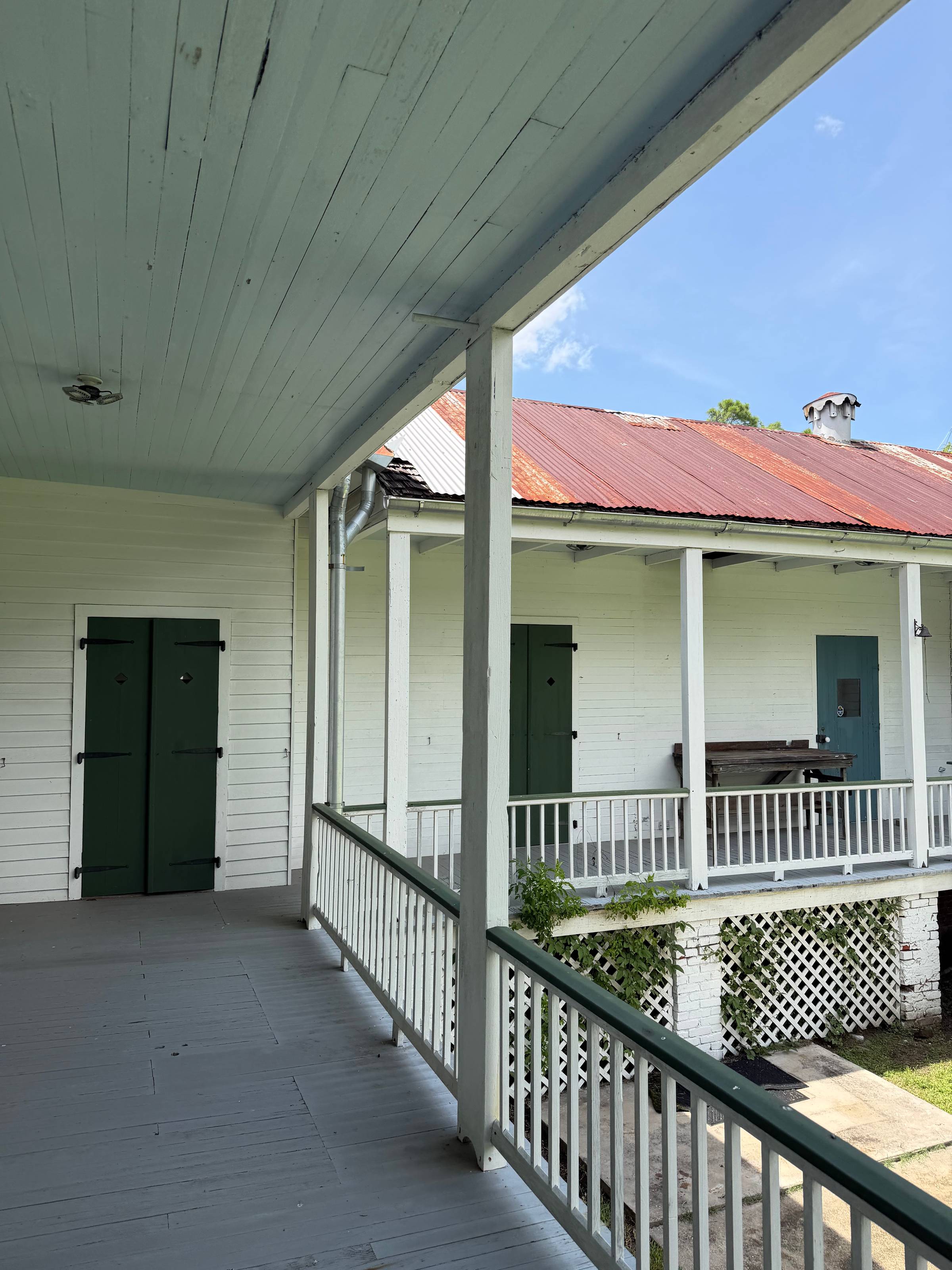 Gallery porch at Woodland Plantation, with green shutters and a rusted tin roof