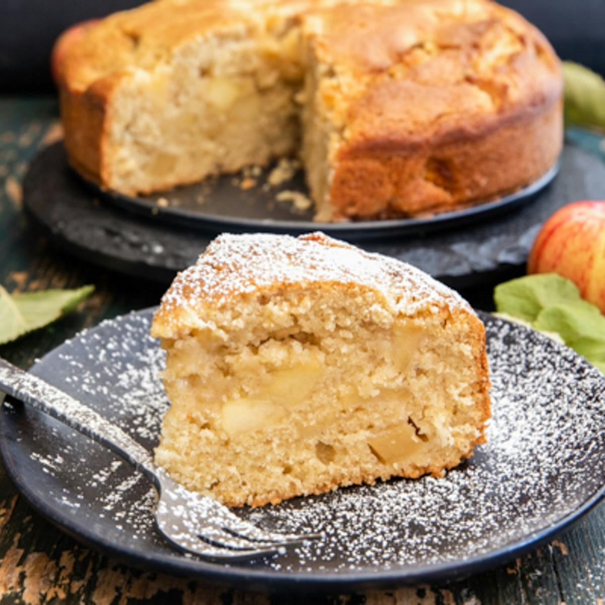 Apple cake slice on a black plate.