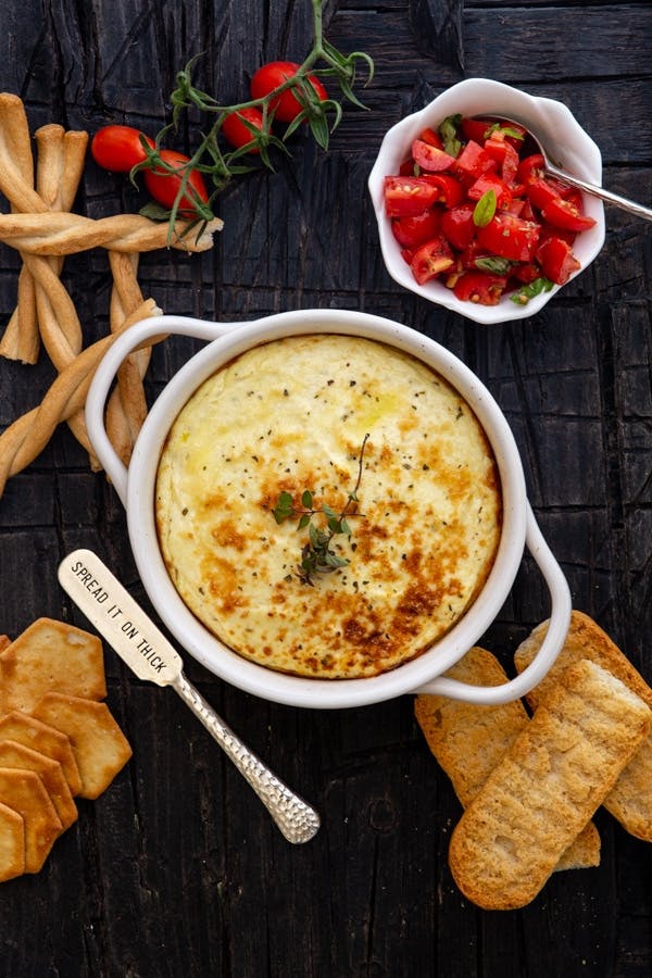 Baked ricotta in a white dish with chopped tomatoes.