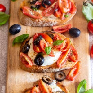 caprese bruschetta on a wooden board.