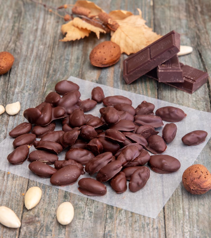 Chocolate covered almonds on a piece of parchment paper.