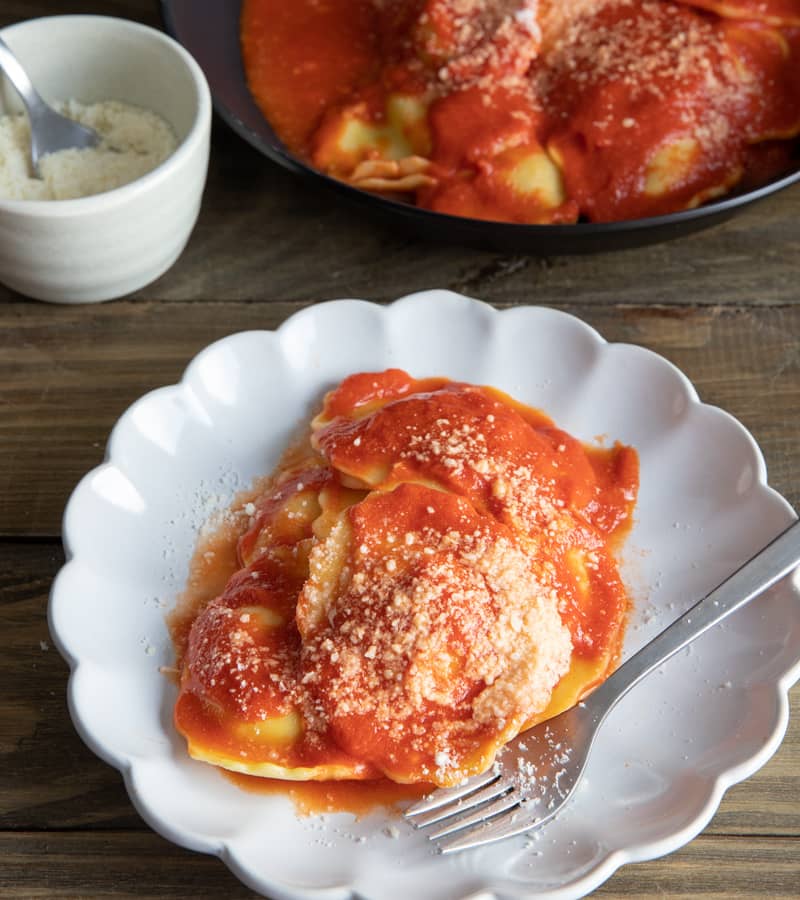 Cream sauce and ravioli on  a white plate.