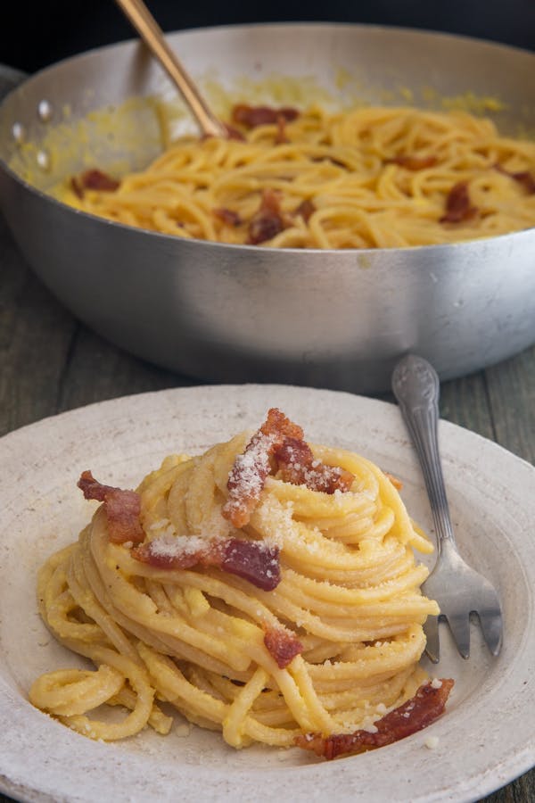 Authentic spaghetti carbonara in a pan on a white plate.