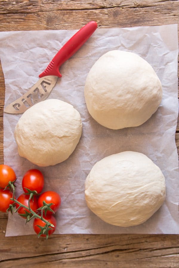 Pizza dough on a parchment paper with cherry tomatoes.