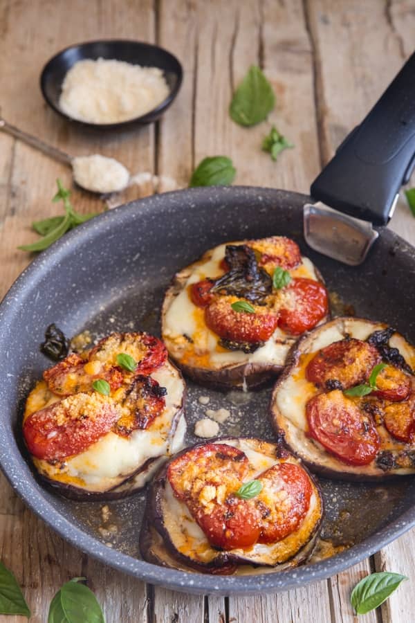 Eggplant and parmesan stacks in a black pan.