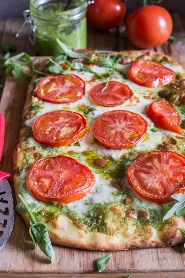 Pesto and Fresh Tomato pizza on a board.