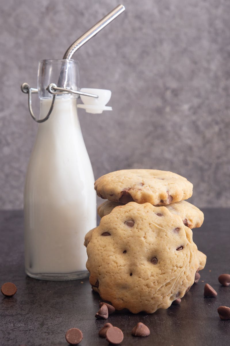 Cookies stacked with a small bottle of milk and a silver straw.