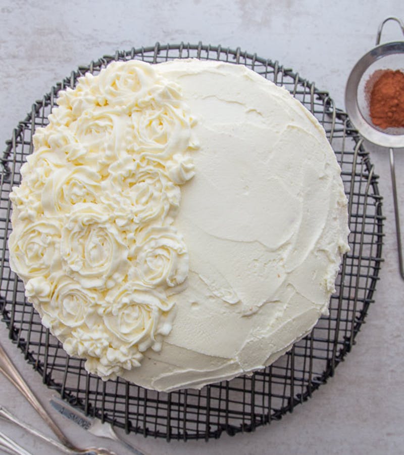 Tiramisu cake on a black wire rack.