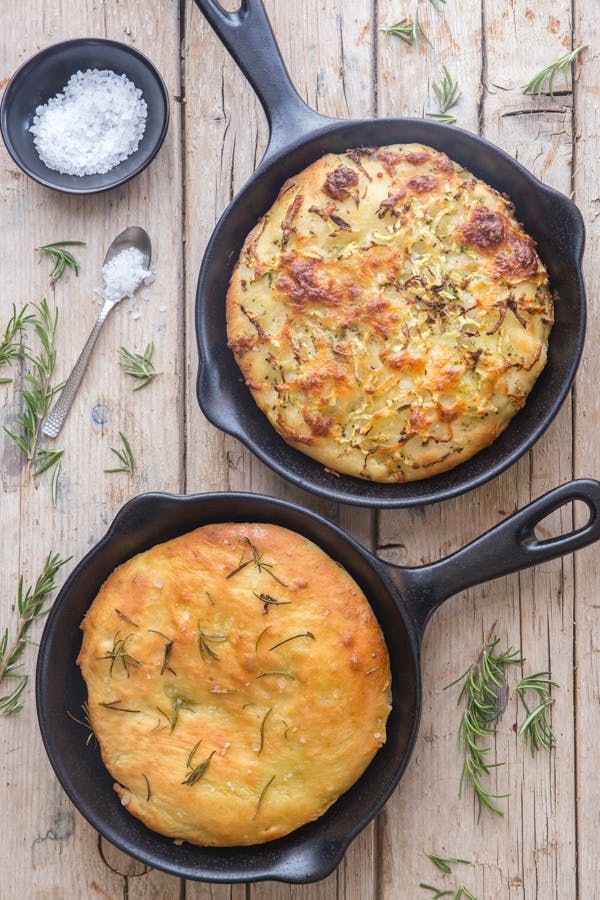 Soft potato focaccia bread in 2 black pans.