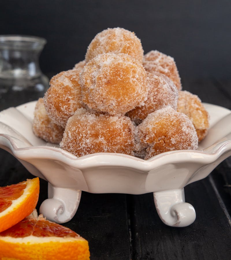 Orange rum castagnole on a white plate.