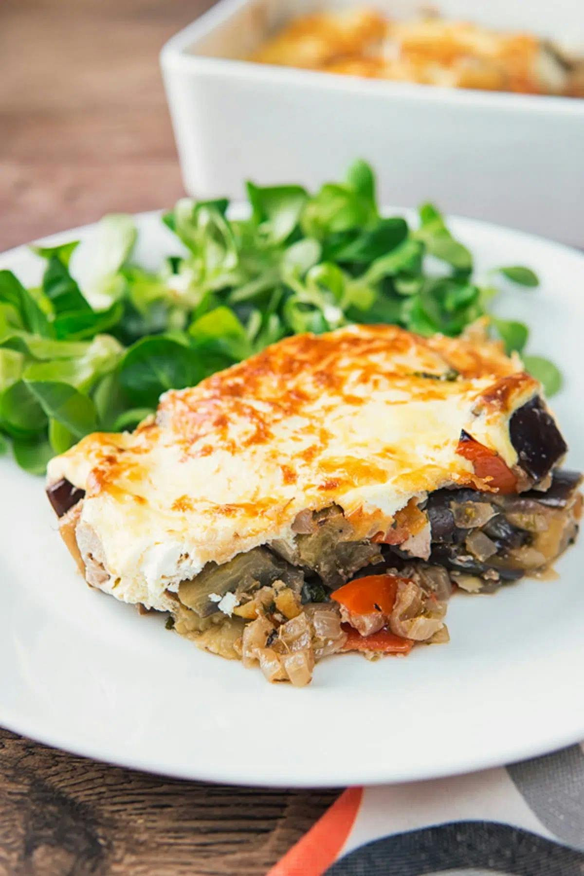 A serving of eggplant casserole on a white plate.