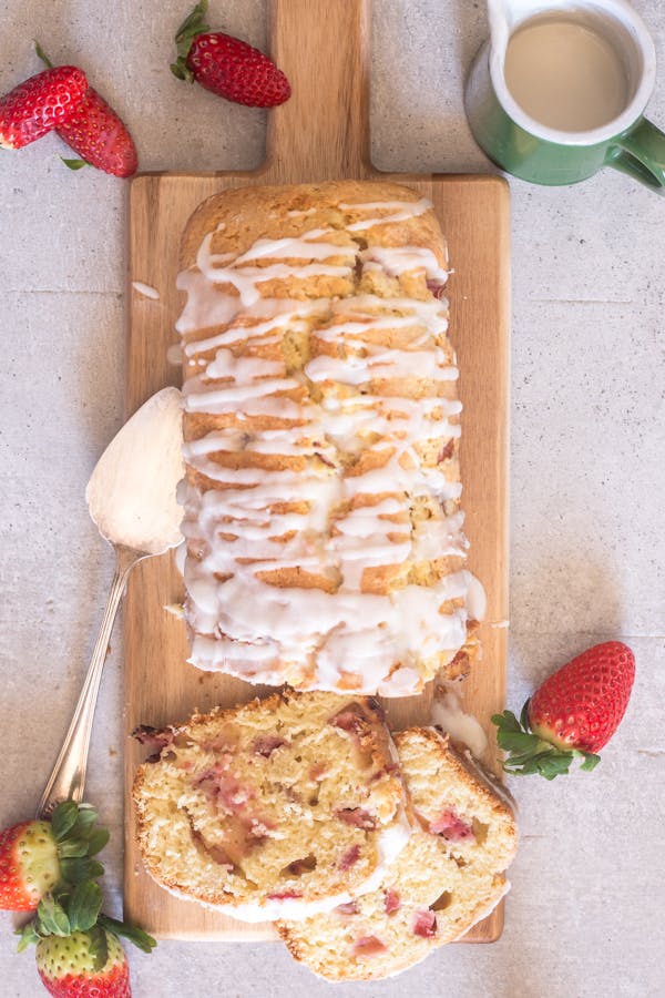 Strawberry bread on a wooden board with 2 slices cut.