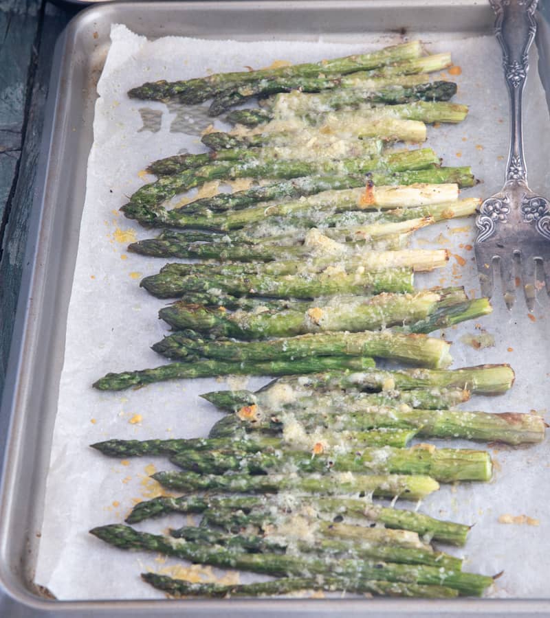 Parmesan roasted asparagus on a parchment paper lined baking sheet.