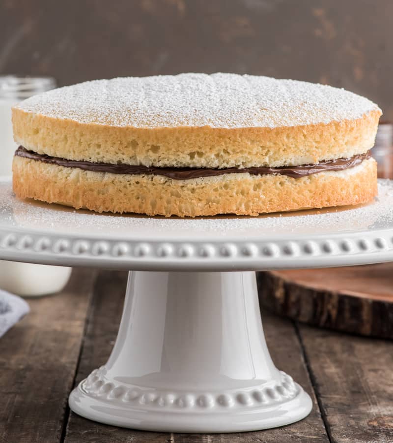 Nutella cake on a white cake stand.