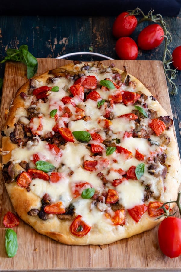 Cheesy Mushroom and Pancetta pizza on a wooden board.