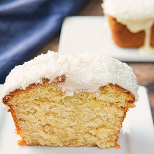 A slice of coconut cake on a white plate.