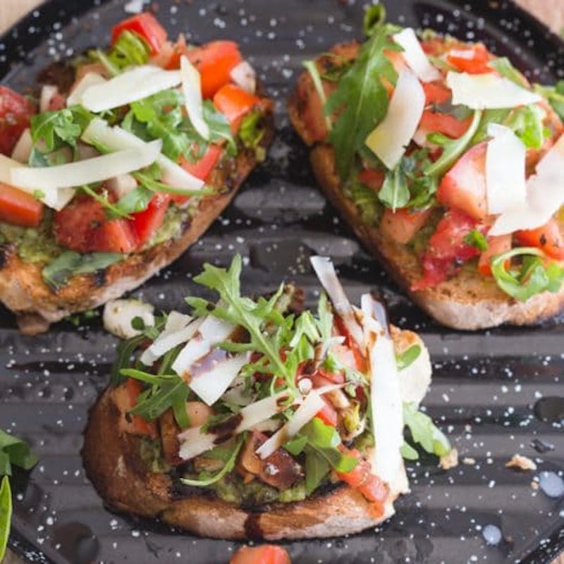 3 bruschetta with pesto, cheese and tomatoes.