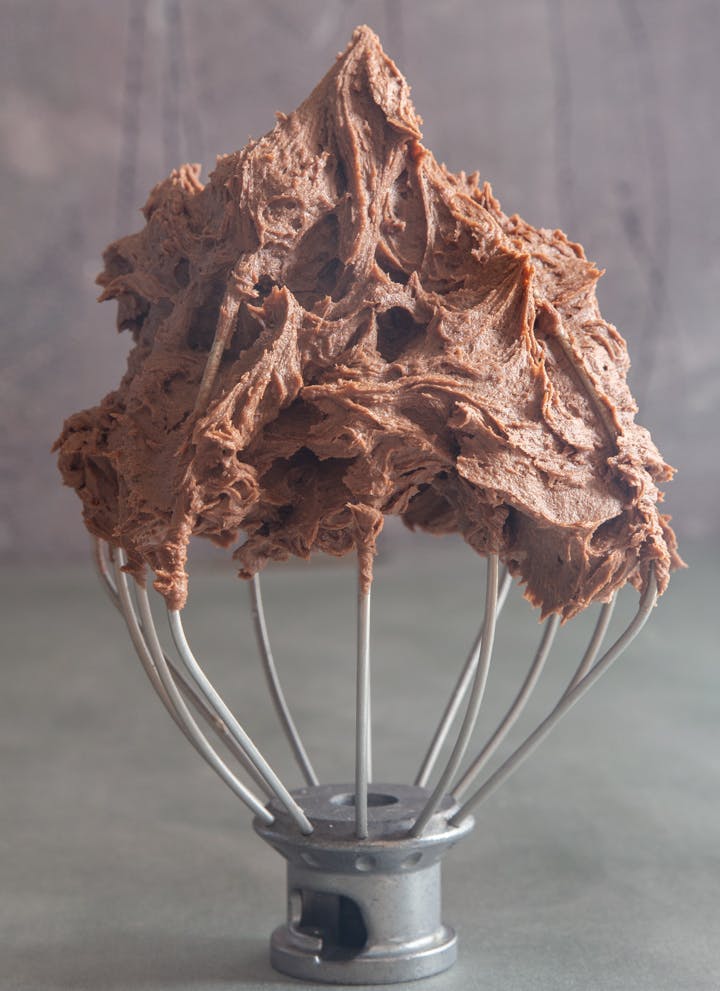 Chocolate buttercream frosting on a wire whisk.