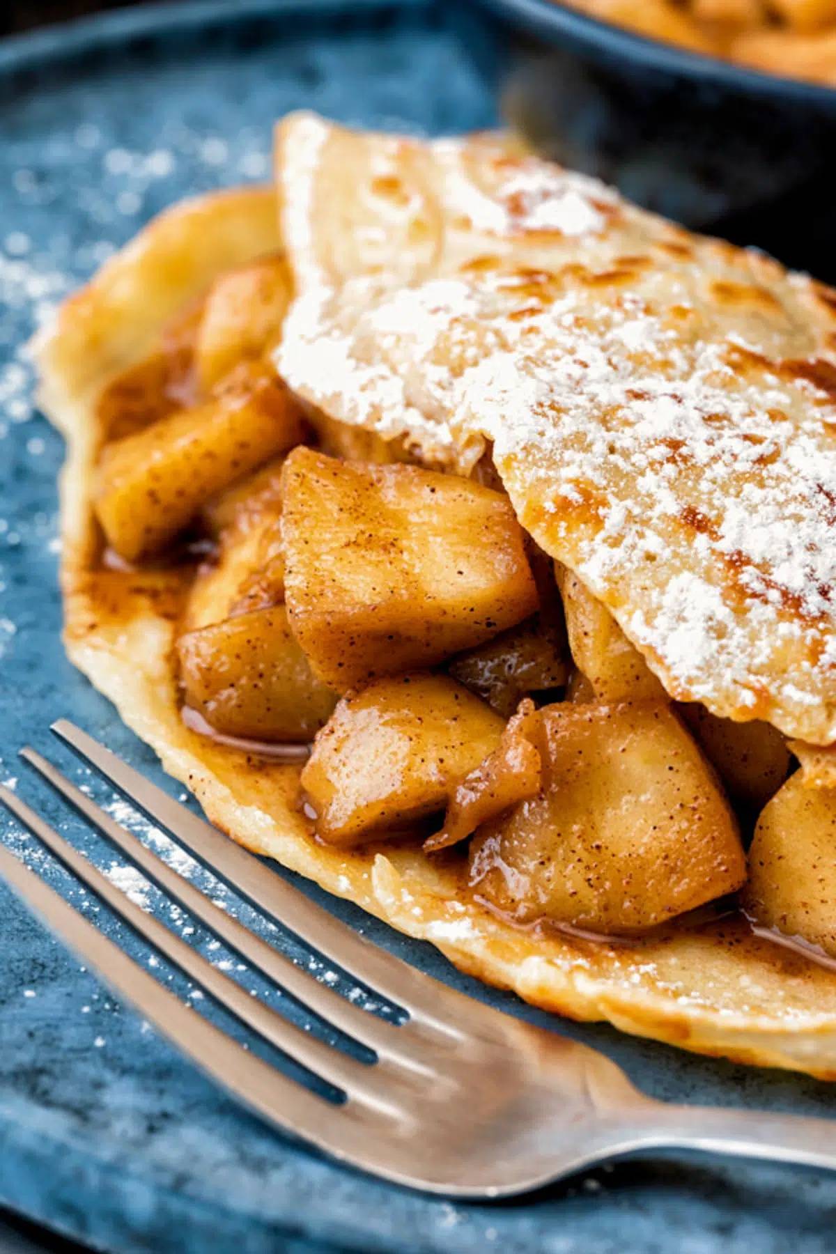Apple pie cinnamon crepes on a blue dish.
