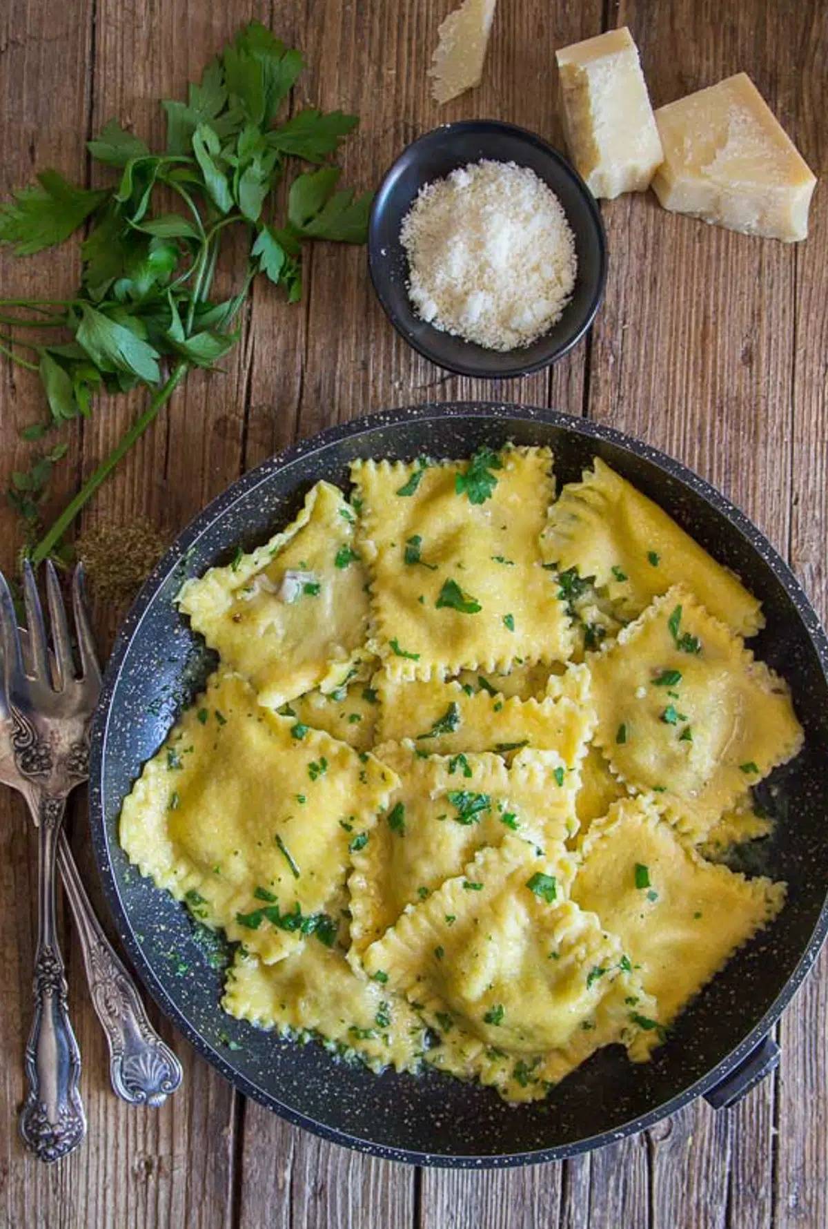 Creamy homemade mushroom ravioli in a black pan.