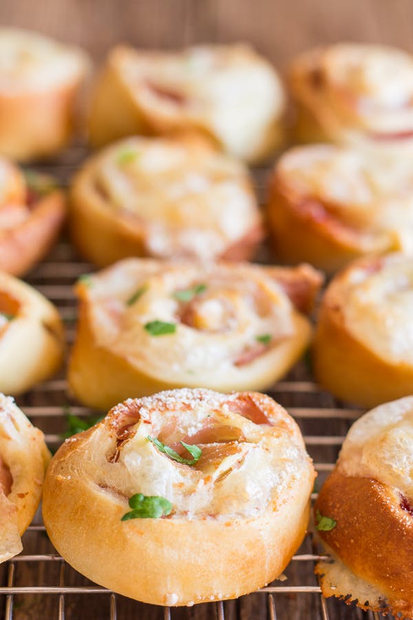 Ham and cheese pizza rollups on a wire rack.