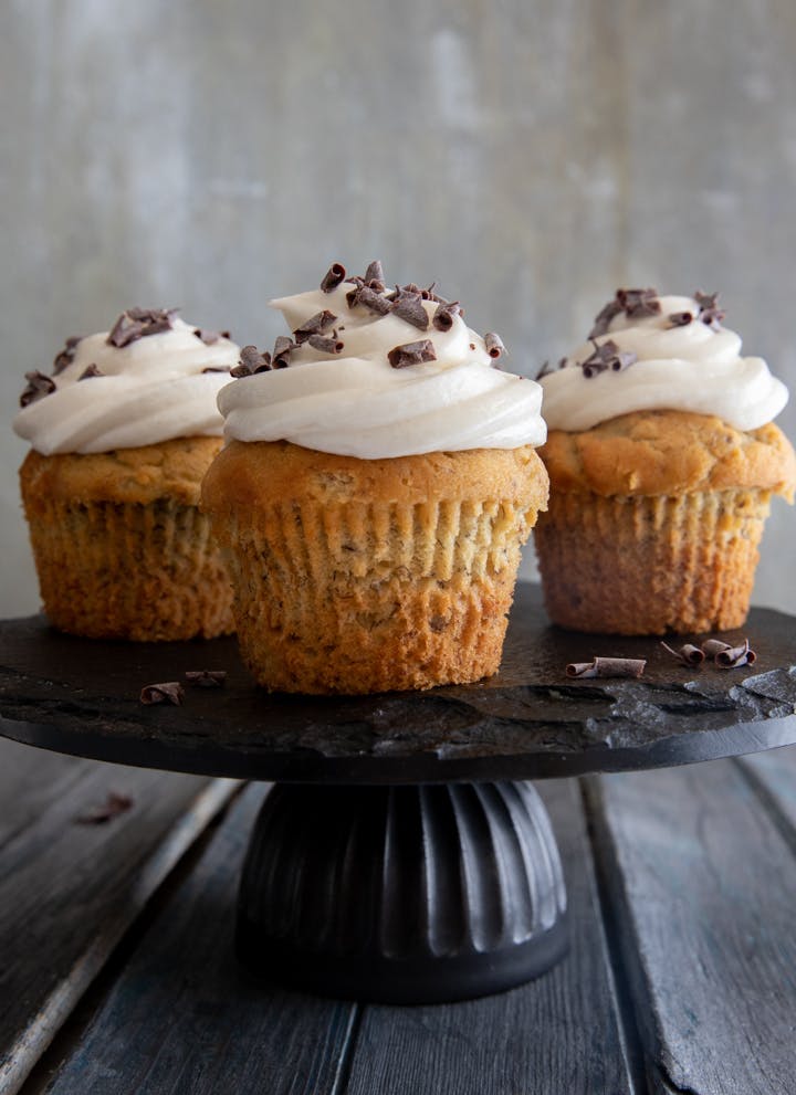 3 Banana cupcakes on a black stand.