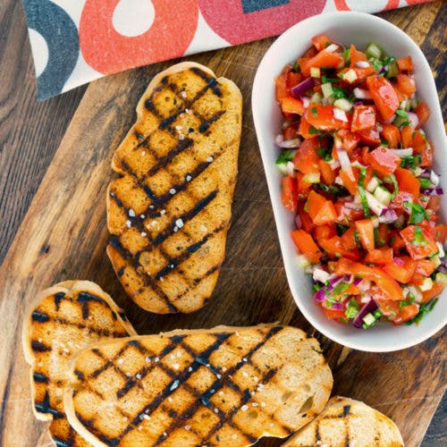 Tomato mixture in a white dish and grilled bread.