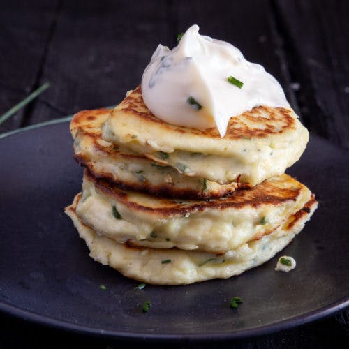 4 fritters stacked with chive mayo dressing on top.