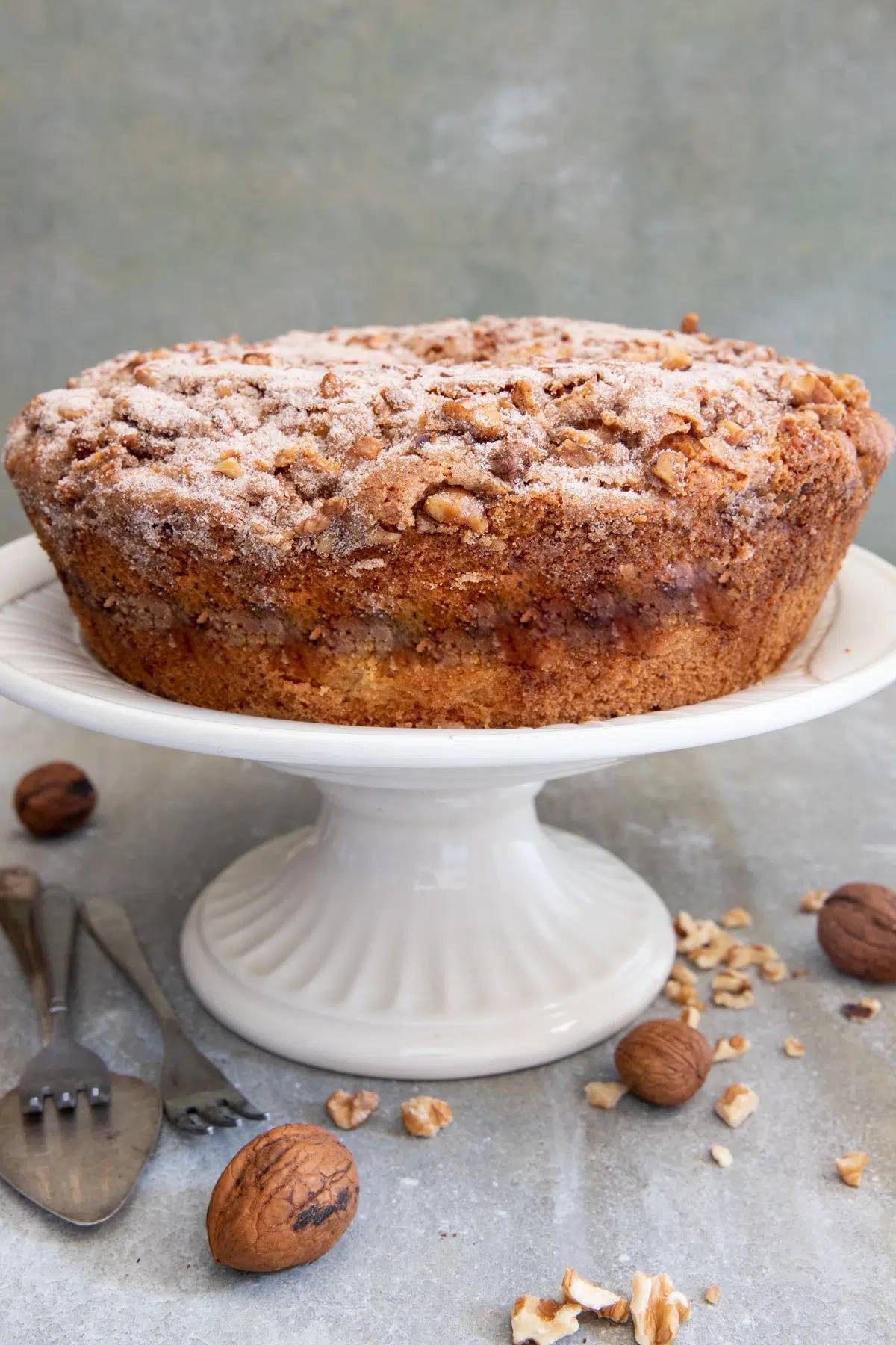 Cinnamon walnut bundt cake on  white cake plate.