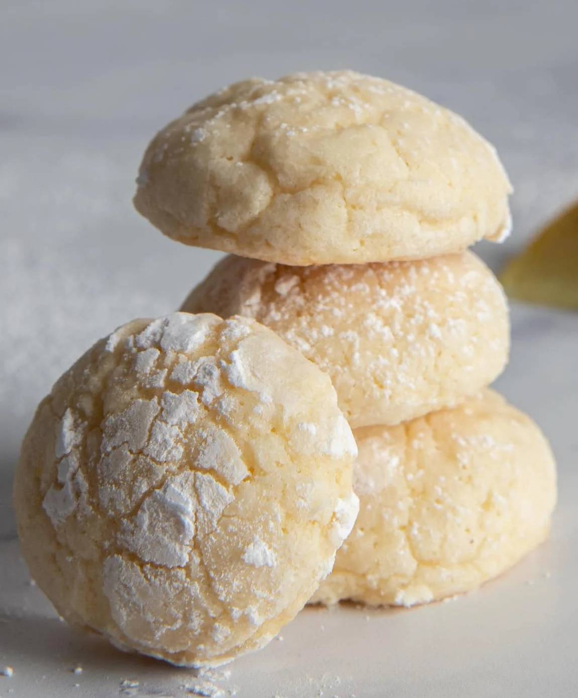 Three lemon ricotta cookies stacked with one leaning.