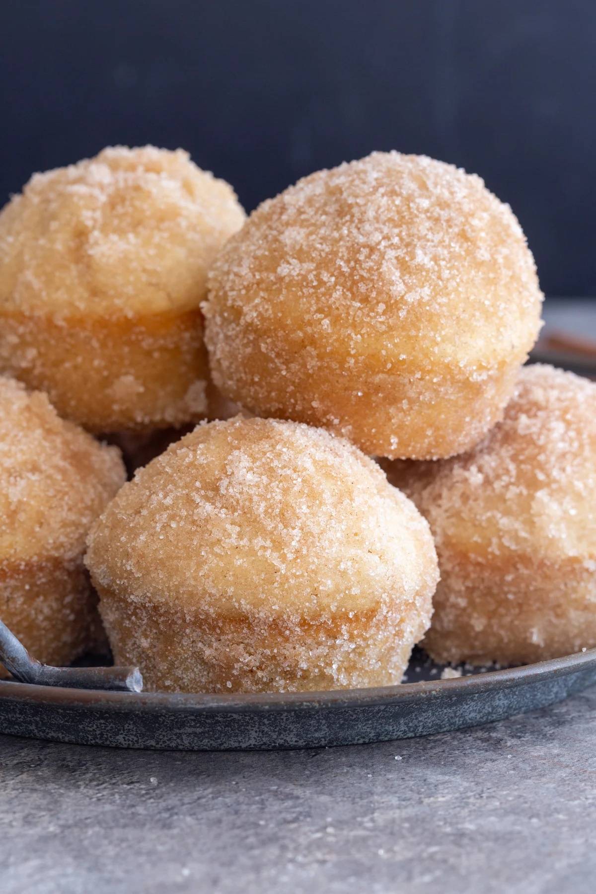 Cinnamon donut muffins on a black tray.