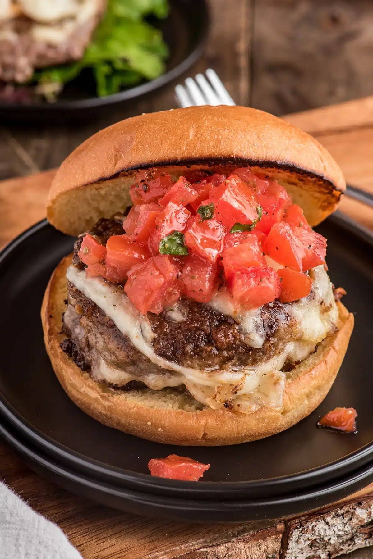 A burger in a bun with tomato topping.
