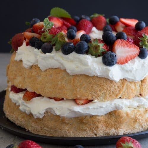 angel food cake filled with cream and fruit on a black plate.