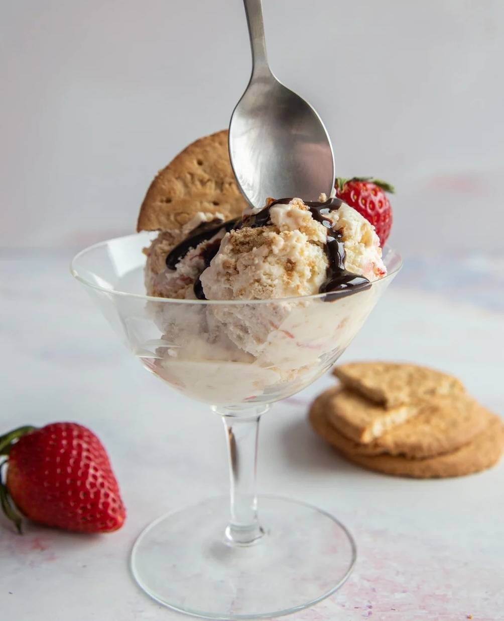 Strawberry cheesecake ice cream in a glass with a spoon.