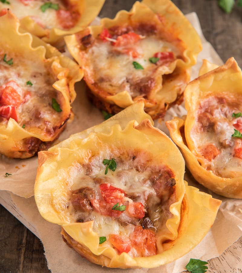 Lasagna cups on a wooden board.