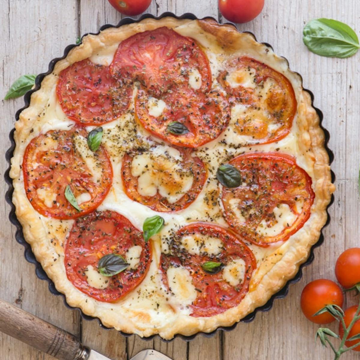 Tomato cheese pie on a white board.