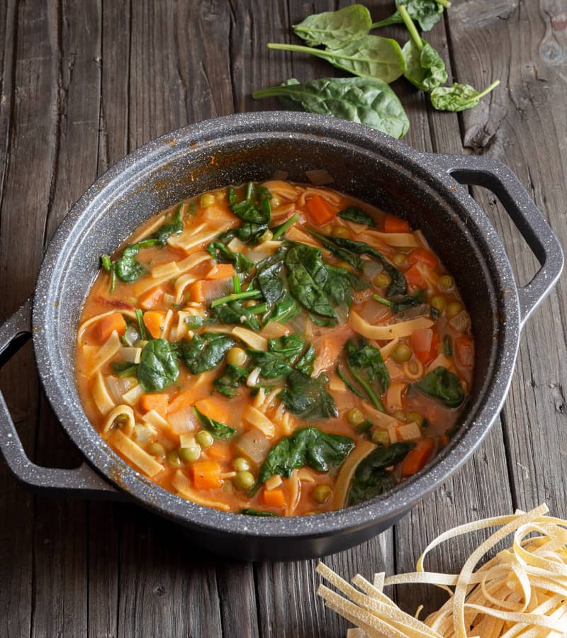 Beef noodle soup in a black pot.