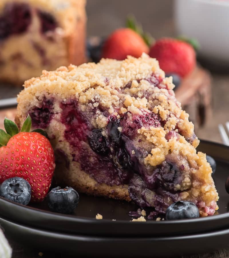 A slice of berry crumb cake on a black plate.