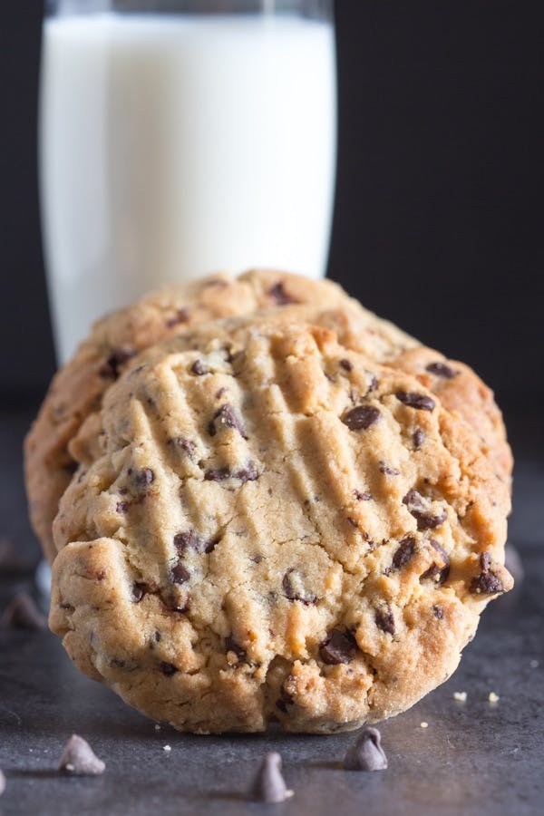 Thick peanut butter chocolate chip cookies with a glass of milk.