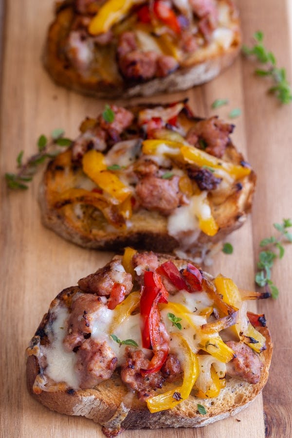 Cheesy sausage bruschetta on a wooden board.