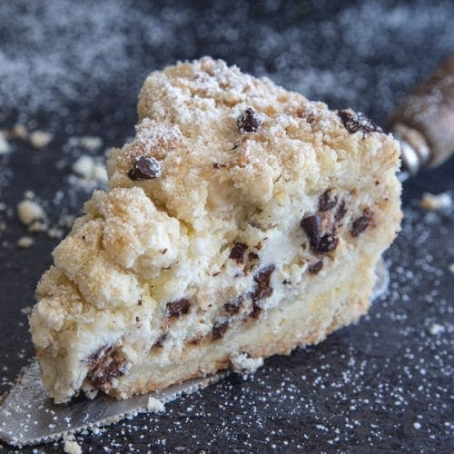 A slice of crumb cake on a black plate.