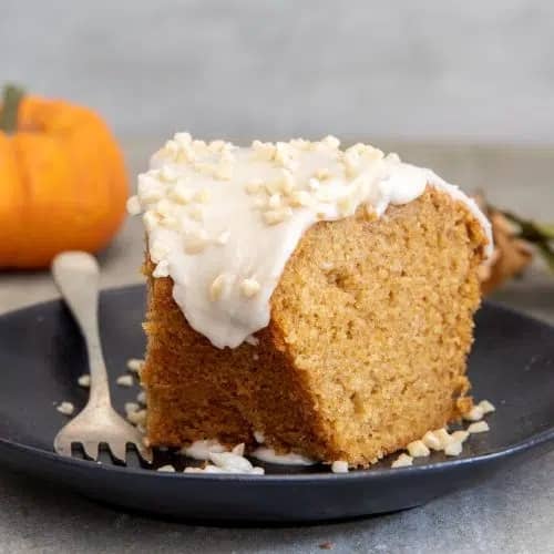 A slice of cinnamon pumpkin cake on a black plate.